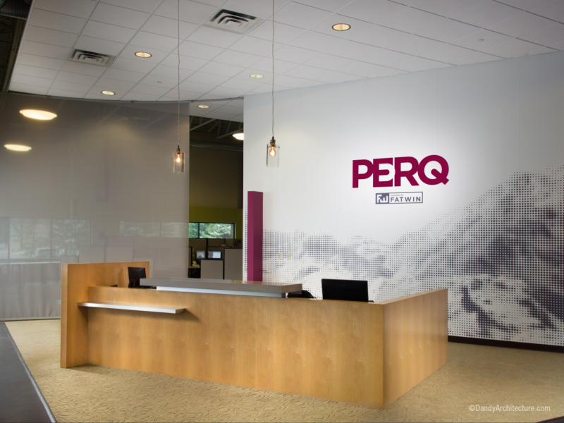 Front desk at business with logo on wall.